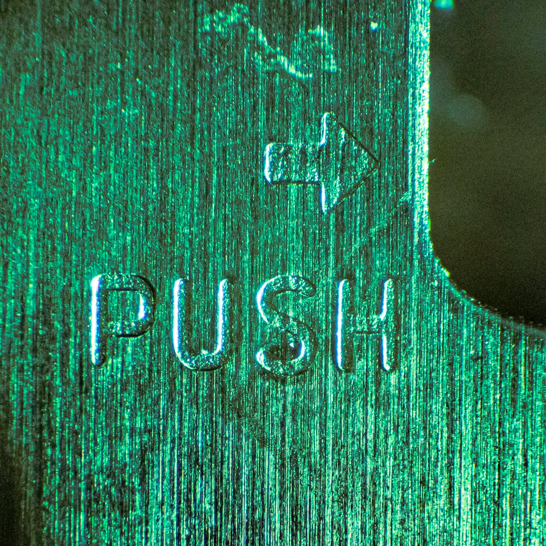 Close-up of the word push embossed on metal.