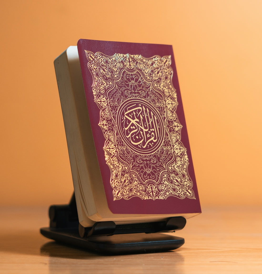 A maroon quran rests open on a stand