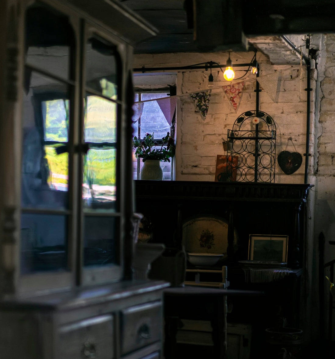 A rustic room with a white brick wall, bunting, and a glowing light bulb